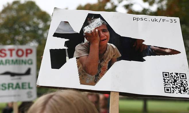 지난 8일 영국 하반트시에서 열린 팔레스타인 연대 시위에서 한 참가자가 가자지구 공습에 사용되는 F-35 전투기 생산에 관련된 영국 기업을 비판하는 손팻말을 들고 있다. 로이터 연합뉴스