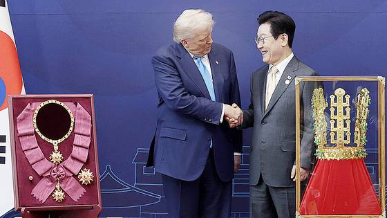 이재명 대통령이 29일 경북 경주박물관에서 도널드 트럼프 미국 대통령에게 '천마총 금관 모형'을 선물한 뒤 악수하고 있다. 왼쪽은 이 대통령이 트럼프 대통령에게 수여한 무궁화 대훈장. 연합뉴스