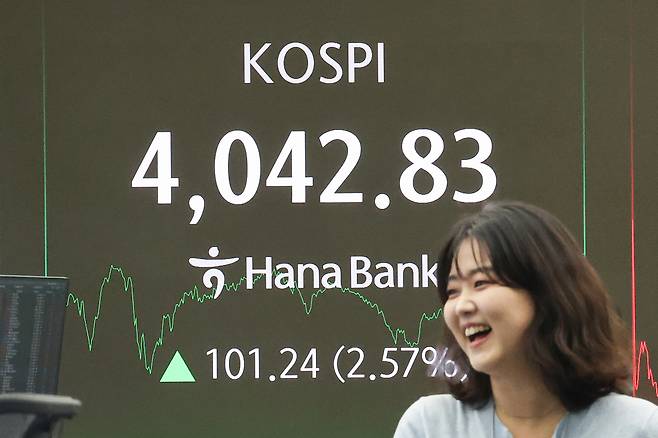 코스피지수가 사상 처음 ‘4000선’을 돌파한 지난 10월 27일 서울 중구 하나은행 본점 딜링룸 현황판 앞에서 은행 직원이 웃고 있다. 연합뉴스