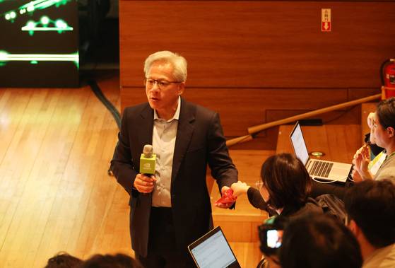 Nvidia CEO Jensen Huang hands out Pepero to reporters at a press briefing held at Gyeongju, North Gyeongsang, on Oct. 31, after delivering his keynote speech for the Asia Pacific Economic Cooperation (APEC) CEO Summit.