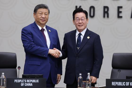 President Lee Jae Myung, right, shakes hands with Chinese President Xi Jinping as he formally hands over the Asia-Pacific Economic Cooperation chairmanship to China for 2026 during the chair handover ceremony at the Gyeongju HICO Convention Center in North Gyeongsang on Nov. 1. [YONHAP]