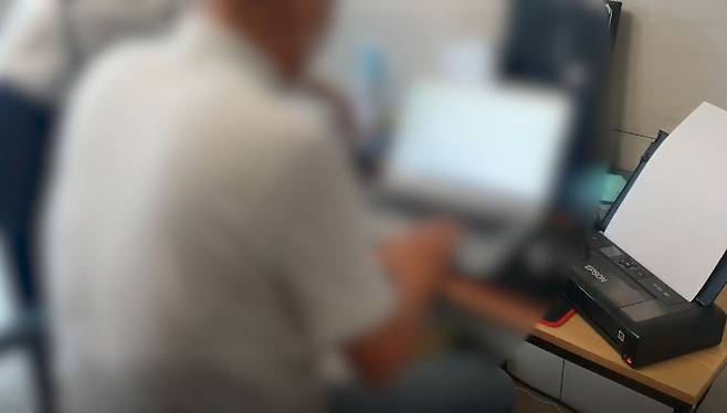 A cyber investigator from the Gyeonggi Nambu Provincial Police Agency explains the execution procedure of an arrest and search warrant to a member of a hacking and phishing ring in front of a laptop used in the crimes.