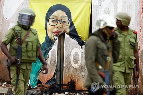 하산 대통령 선거 포스터 앞을 지나는 탄자니아 군경 [로이터 연합뉴스 자료사진. 재판매 및 DB 금지]