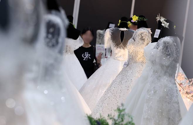 지난 7월 서울 강남구 삼성동 코엑스에서 열린 2025 추계 웨덱스 웨딩 박람회에서 예비 부부들이 전시된 드레스를 살펴보고 있다./뉴스1