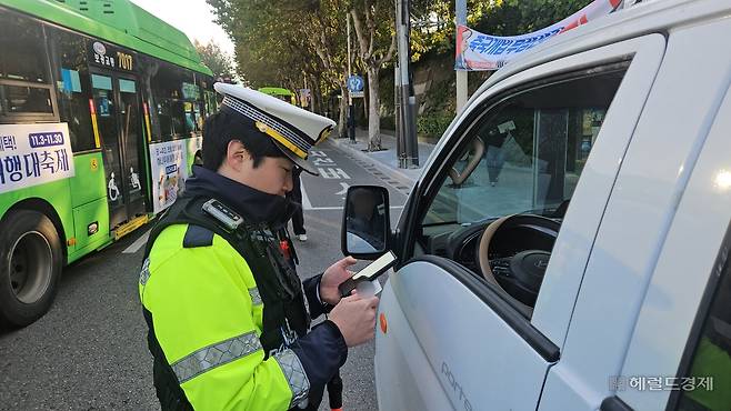 4일 오전 서울 서대문경찰서 소속 교통경찰이 연세대 교차로 앞에서 꼬리물기를 하다 걸린 트럭 운전자에게 범칙금 4만원을 부과하고 있다. 이용경 기자