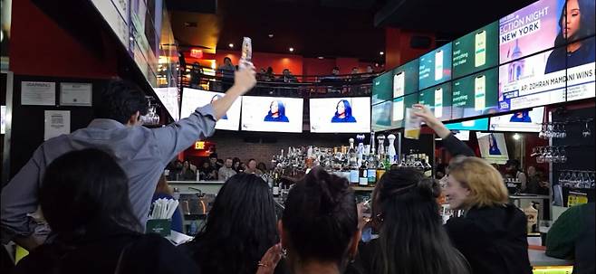 4일(현지시간) 미국 뉴욕시장 선거에서 조란 맘다니 미국 민주당 후보의 당선이 확정적이라는 방송 보도가 나오자 지지자들이 환호하고 있다. 사진 왼쪽 TV 화면에 맘다니의 당선 확정을 알리는 방송 자막이 보인다. /사진=심재현 특파원