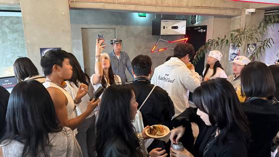 People eat, drink and dance in front of the DJ booth at the “Early Bud” party. [WOO JI-WON]