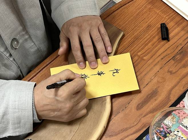 백양사 주지 무공스님이 1호 결혼 커플에게 금일봉 봉투에 축화혼 글씨를 쓰고 있는 모습. <조계종사회복지재단>