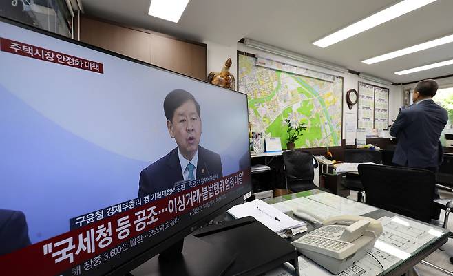 A television at a real estate agency in Seoul airs a government announcement on measures to stabilize the housing market on Oct. 15. All 25 districts in Seoul and 12 areas in Gyeonggi Province were designated as regulated zones, including speculative and overheated speculation areas. [YONHAP]