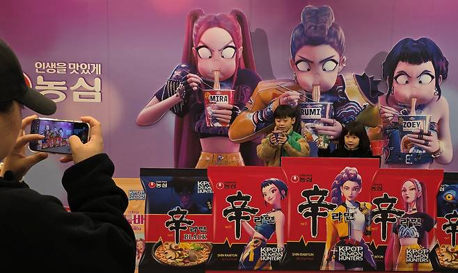 지난 7일 경북 구미시 구미역 앞에서 열린 '2025 구미 라면 축제' 행사장을 찾은 방문객들이 넷플릭스 애니메이션 영화 '케이팝 데몬 헌터스' 등장 인물들이 라면을 먹는 모습을 배경으로 기념사진을 찍고 있다. /뉴스1