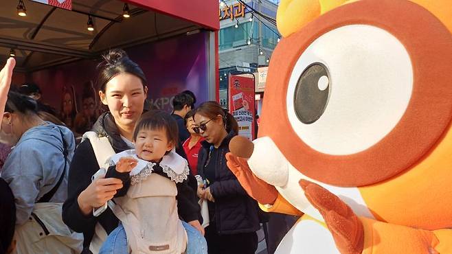 지난 7일 경상북도 구미시에서 열린 '2025 구미라면축제'에 방문한 엄마와 아이가 농심 너구리 캐릭터와 인사를 하고 있다. 사진=이환주 기자