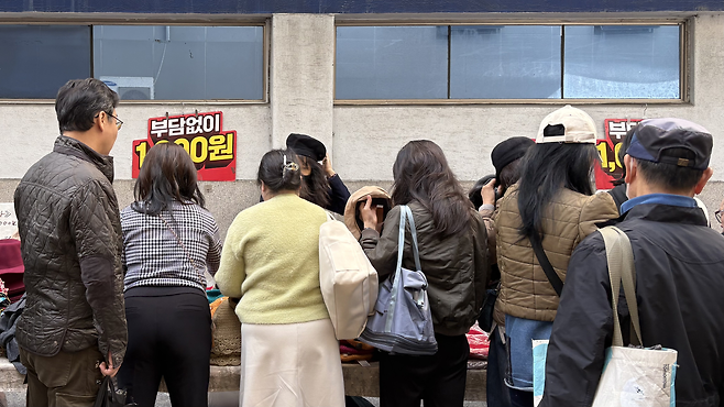 지난 9일 찾은 서울 종로구 동대문 일요시장 모자 노점에서 사람들이 모자를 써보고 있다.  박연수 기자