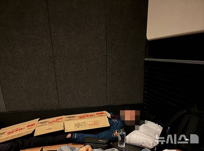 [서울=뉴시스]경주에서 열린 아시아태평양경제협력체(APEC) 정상회의 현장에서 근무복을 입은 경찰관이 어두운 실내 바닥에 누워 종이박스를 덮고 잠을 청하고 있다.(사진=전국경찰직장협의회 제공)