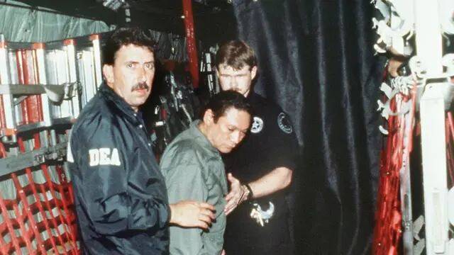 1990년 1월 3일 미국 마약단속국 직원들이 항복한 파나마의 독재자 마누엘 노리에가 장군을 체인에 묶어 미 군용기에 태우고 있다.