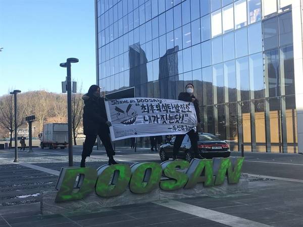 ▲2021년 2월 28일 이은호, 강은빈 활동가가 분당두산타워 두산 로고 조형물에 초록색 스프레이를 뿌리는 직접행동에 나섰다. ⓒ청년기후긴급행동
