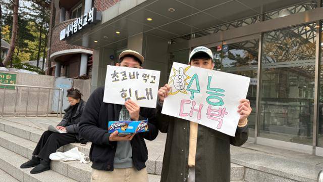 13일 서울 종로구 경복고 앞에서 황모씨와 왈리가 수험생들에게 간식을 건네고 있다. 문지수 기자