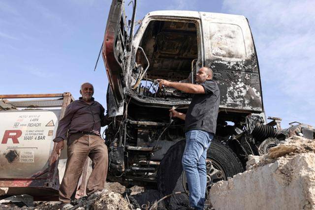한 팔레스타인인이 이달 2일 서안지구 칼킬리야의 한 마을에서 유대인 정착민들이 불태운 트럭을 가리키고 있다. 칼킬리야=AFP 연합뉴스
