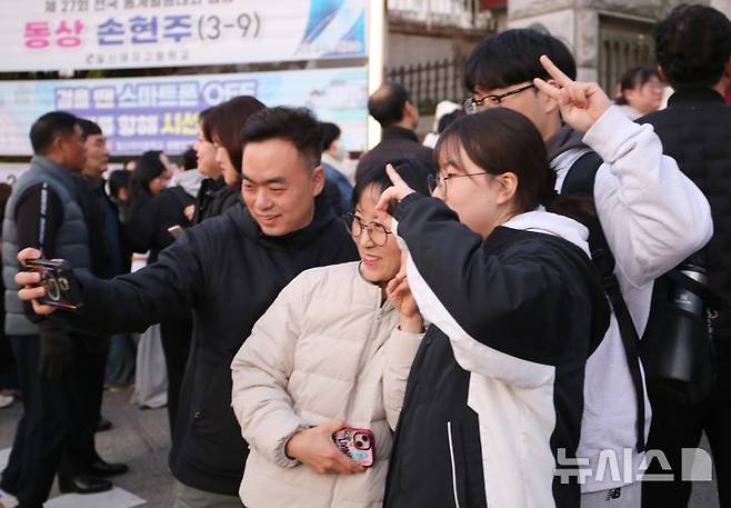 [청주=뉴시스] 서주영 기자 = 2026학년도 대학수학능력시험일인 13일 충북 청주시 일신여자고등학교 앞에서 학부모와 수능을 끝낸 수험생 자녀가 함께 기념촬영을 하고 있다. 2025.11.13. juyeong@newsis.com