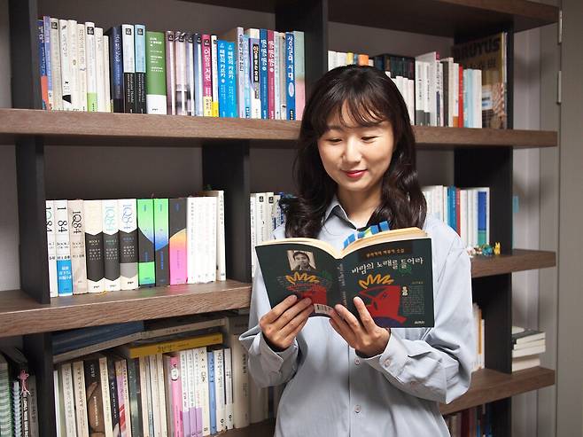 이지수 번역가가 88권의 하루키 컬렉션이 진열된 자신의 서가 앞에서 그가 가장 처음 읽은 하루키 소설 ‘바람의 노래를 들어라’를 펼쳐보고 있다. 본인 제공