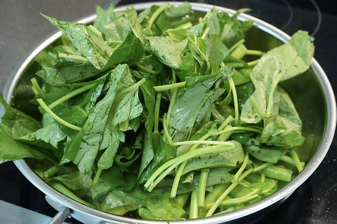 센 불에 공심채 잎과 줄기를 함께 어우러지도록 빠르게 볶아내는 과정