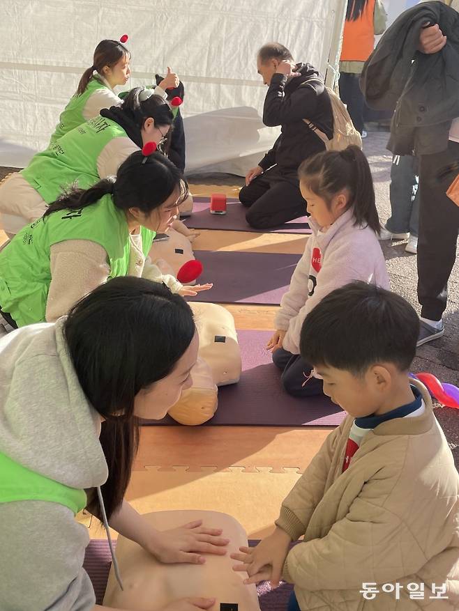 마인드앤매뉴얼이 15일 서울 광진구 어린이대공원에서 열린 ‘2025 심장병 예방을 위한 한걸음 더 걷기대회’에 마련한 부스에서 시민들이 심폐소생술(CPR) 실습 체험을 하는 모습. 마인드앤매뉴얼 제공