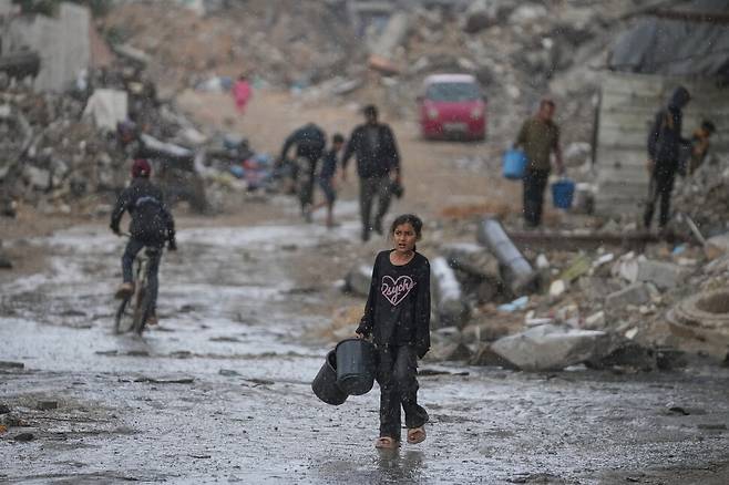 14일(현지시각) 가자지구 가자시티에 폭우가 쏟아지는 가운데 한 팔레스타인 소녀가 물을 긷기 위해 빈 물통을 들고 걷고 있다. 폭우로 난민 캠프의 천막들이 물에 잠겨 팔레스타인 주민들이 고통을 호소하고 있다. AP 연합뉴스