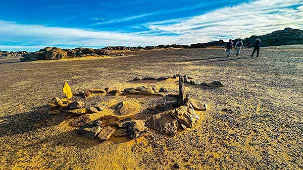 황량한 벌판 위에 돌로 둘러싼 작은 원형 무덤, 투아레그 남자의 무덤으로 머리는 이슬람의 성지 메카 방향을 향하고 있다.