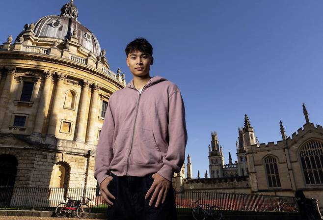 한 윌호프트-킹이 옥스포드대학교를 배경으로 기념 사진을 찍고 있다.  가디언 캡처
