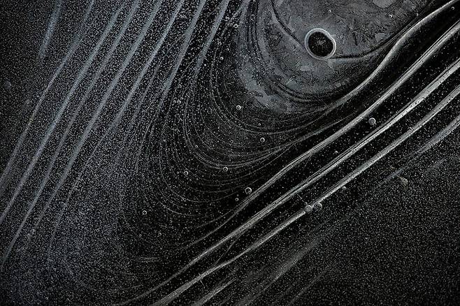 The Happy voyager #02, 2025, 철원 , 사진가는 어느 겨울 얼음 낚시를 갔다가 발밑에 얼어붙은 강 속에 공기방울이 마치 우주의 모습처럼 보였다고 했다. 이 작은 생각에서 출발해 전국을 돌며 얼음 속 우주의 행성 같은 무늬를 찾아 작업했다. / 사진가 주기중