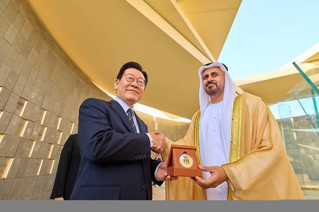 이재명 대통령이 17일(현지시간) 아랍에미리트연합(UAE) 현충원 격인 ‘와하트 알 카리마’를 방문해 디얍 대통령 직속 개발·보훈 사무국 부의장으로부터 기념메달을 받은 뒤 악수하고 있다. 연합뉴스