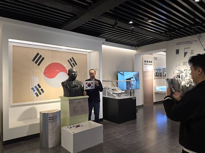 충칭 임시정부청사에서 김구선생 동상옆에서 태극기를 찍고 기념촬영하는 한국인 관광객들