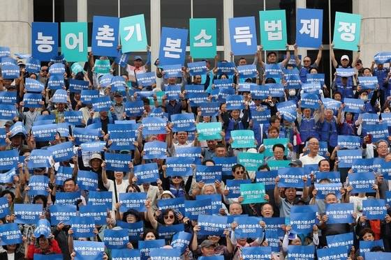 서울 여의도 국회 본청 앞 계단에서 열린 농어촌기본소득법 제정 촉구 기자회견에서 참가자들이 구호를 외치고 있다. [연합뉴스]