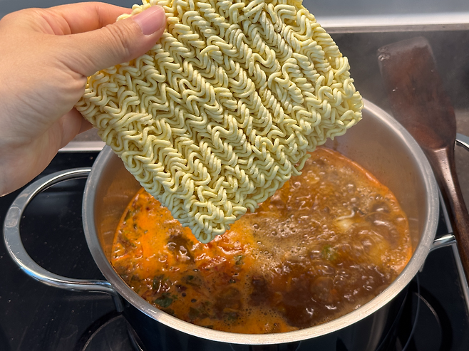 볶은 굴에 물을 붓고 끓인 뒤 라면 사리를 넣는 굴라면 레시피 과정