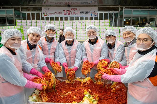 문갑 호반건설 경영부문대표(왼쪽 두번째 )와 호반그룹 임직원들, 자원봉사자들이 지난 20일 서초구청 광장에서 지역 이웃들에게 전달할 김장 김치를 담그고 있다. [호반그룹]