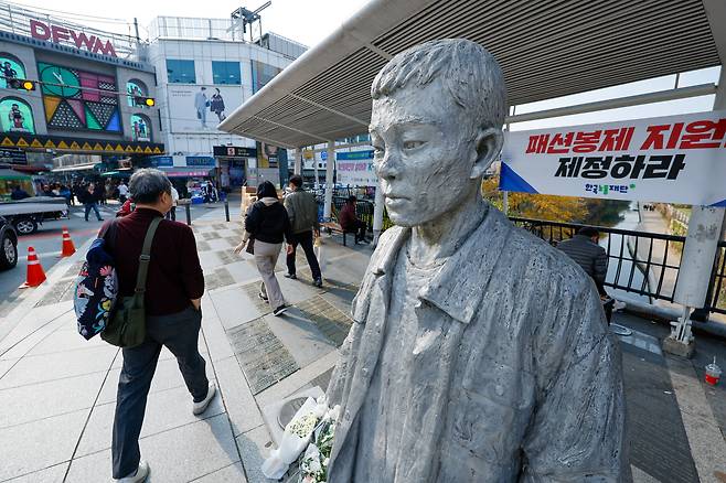 전태일 열사 55주기인 11월 13일 서울 종로구 전태일다리 전 열사 동상 뒤로 패션봉제 지원법 제정을 촉구하는 현수막이 걸려 있다. /뉴스1