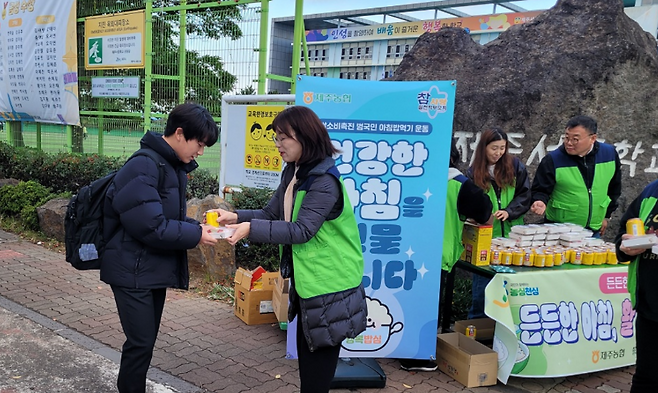 제주농협과 학부모회 관계자들이 백설기와 식혜를 학생들에게 건네며 ‘아침 챙겨가라’고 응원하는 모습. (제주농협 제공)
