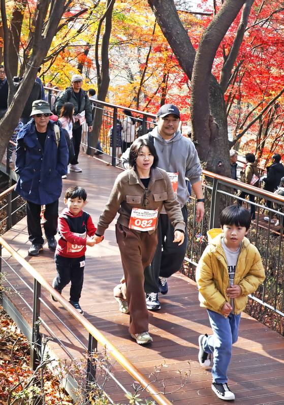 A family walks along a trail on Mount Namsan in Jung District, central Seoul, during the 2025 Seoul Eco Hiking Festa's family-themed hike on Nov. 22. [PARK SANG-MOON]