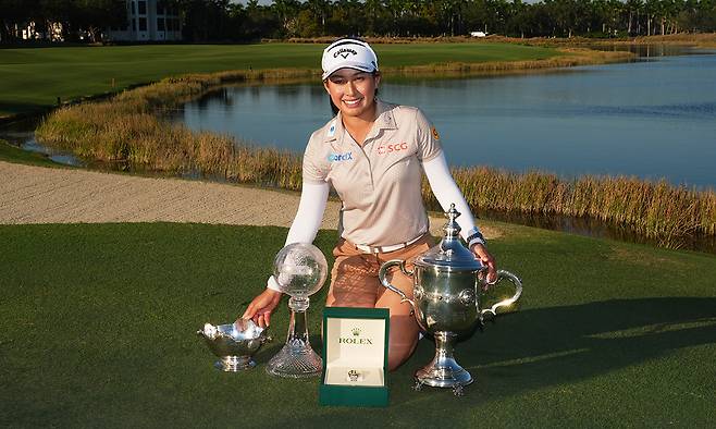 지노 티띠꾼(태국)이 24일 미국 플로리다주 네이플스의 티뷰론 골프클럽에서 열린 LPGA 투어 시즌 최종전 CME그룹 투어 챔피언십에서 우승한 뒤 시즌 평균타수 1위에게 주는 베어 트로피(왼쪽부터)와 대회 우승 트로피, 올해의 선수 트로피를 세워두고 기념 촬영을 하고 있다. 네이플스=AFP연합뉴스
