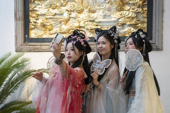 Tourists from Korea wearing hanfu (Chinese traditional dress) take a selfie at Yuyuan Garden Mall in Shanghai on July 21. [XINHUA NEWS AGENCY]