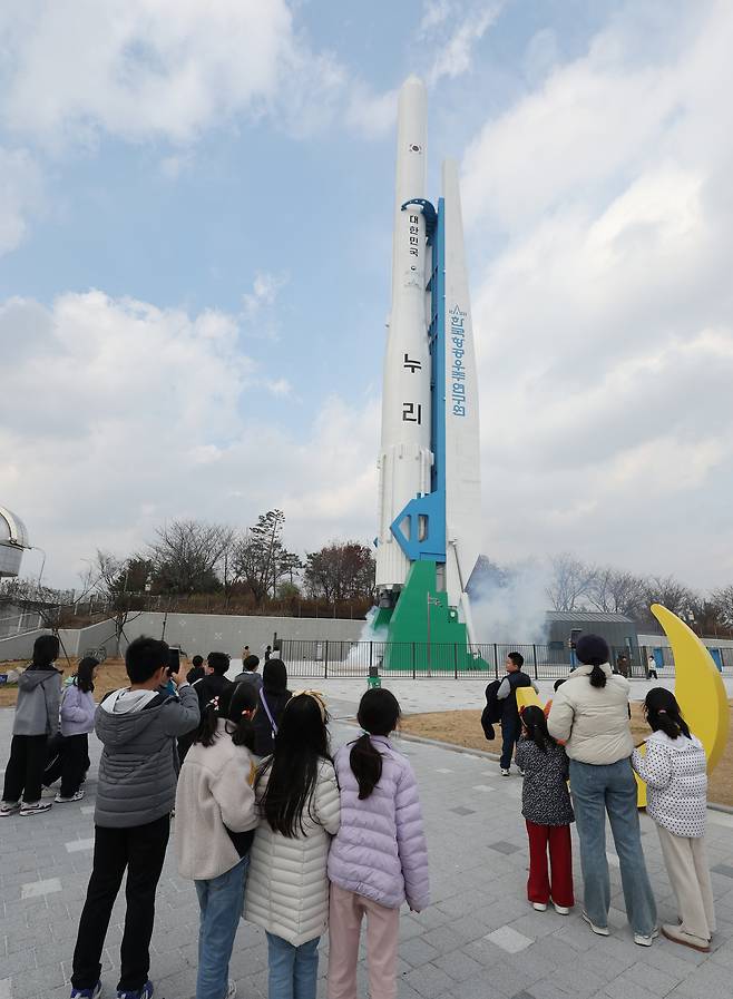 Children watch the model of a Nuri space rocket being erect at the Gwacheon National Science Museum in Gwacheon, Gyeonggi, on Nov. 23. [YONHAP]