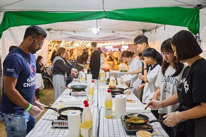 ‘2025 별바다부산 나이트 페스타’ 나이트 마켓 현장에서 국내외 관광객들이 찌짐(전) 만들기 체험을 하고 있는 모습. 부산관광공사 제공