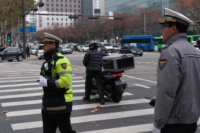 한 운전자가 오토바이를 끌고 횡단보도를 건너고 있다. 황동건 기자