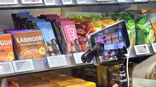 A Chinese tourist livestreams Korean products at Olive Young in Hongdae, western Seoul, on Nov. 21.  [NOH YU-RIM]