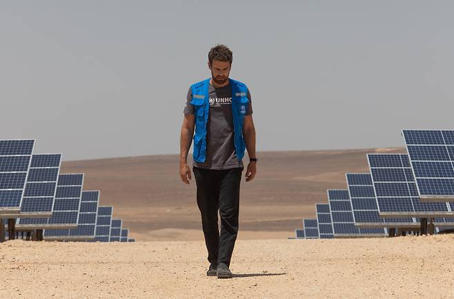 Actor Theo James walks amid solar panels powering the Azraq Refugee Camp in Jordan on July 25, 2023. The solar plant, which was funded by IKEA Foundation, provides the camp with 79 percent of its electricity needs. [UNITED NATIONS HIGH COMMISSIONER FOR REFUGEES]