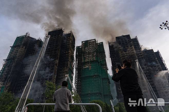[홍콩=AP/뉴시스] 홍콩 신계의 ‘웡 푹 코트(Wang Fuk Court)’ 고층 아파트 단지에서 화재 발생 하루 가량이 지난 27일에도 검은 연기를 내뿜으며 완전 진화되지 않고 있다. 2025.11.27.