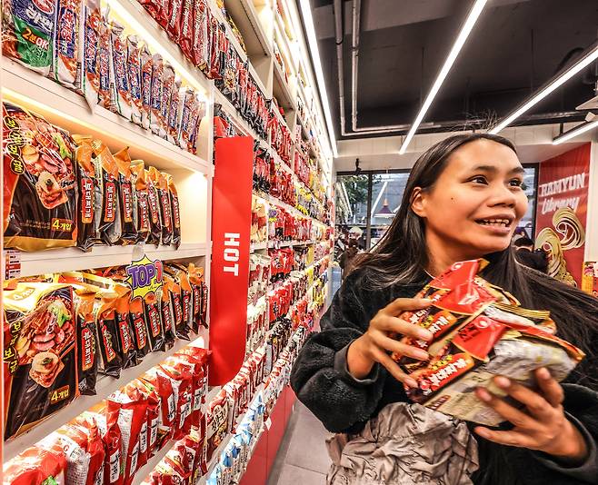 지난 24일 서울  홍대 앞 라면 특화 편의점 CU ‘라면 라이브러리’에서 한 외국인 관광객이 ‘부대찌개면'을 품에 안고 기뻐하고 있다. 부대찌개 라면 코너에는 판매 1위를 뜻하는 'TOP1' 팻말이 부착돼있다. /주민욱 영상미디어 기자