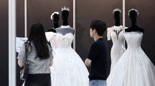 7월 6일 서울 강남구 삼성동 코엑스에서 열린 ‘2025 추계 웨덱스 웨딩 박람회’에서 예비 부부들이 전시된 드레스를 살펴보고 있다. 뉴스1