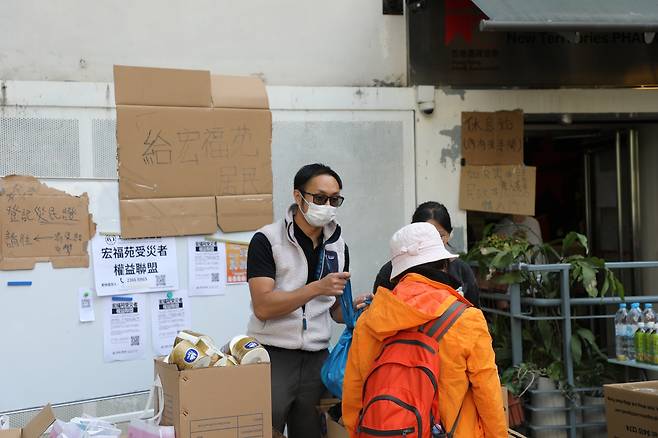 화재 피해자 위해 구호품 나눠주는 자원봉사자 29일(현지시간) 오전 대형 화재가 발생했던 홍콩 북부 타이포의 웡 푹 코트 인근의 아파트 단지 앞에서 자원봉사자가 구호품을 나눠주고 있다. [촬영 박수현]