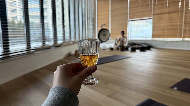 The writer holds a glass of whisky as a meditation instructor rubs singing bowls during a whisky meditation session at High1 Resort in Jungseon County, Gangwon, held on Nov. 20 [WOO JI-WON]