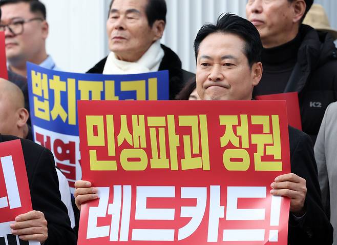 국민의힘 장동혁 대표가 30일 강원 춘천시청 인근에서 열린 민생회복 법치수호 국민대회에서 정부를 비판하는 메시지가 담긴 손팻말을 들고 있다. 연합뉴스